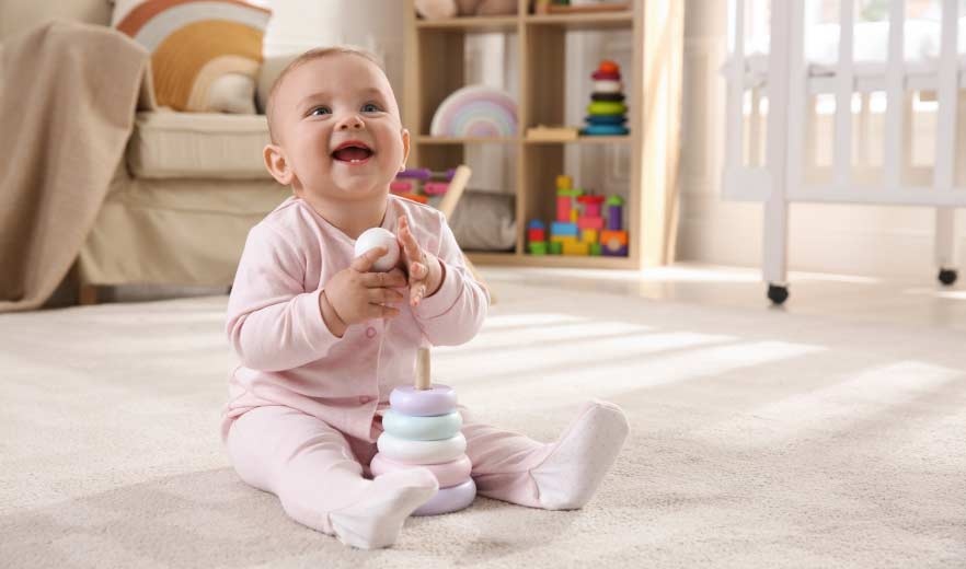 Ein lachendes Baby sitzt in seinem Kinderzimmer auf dem Boden und spielt mit einem kleinen Ball